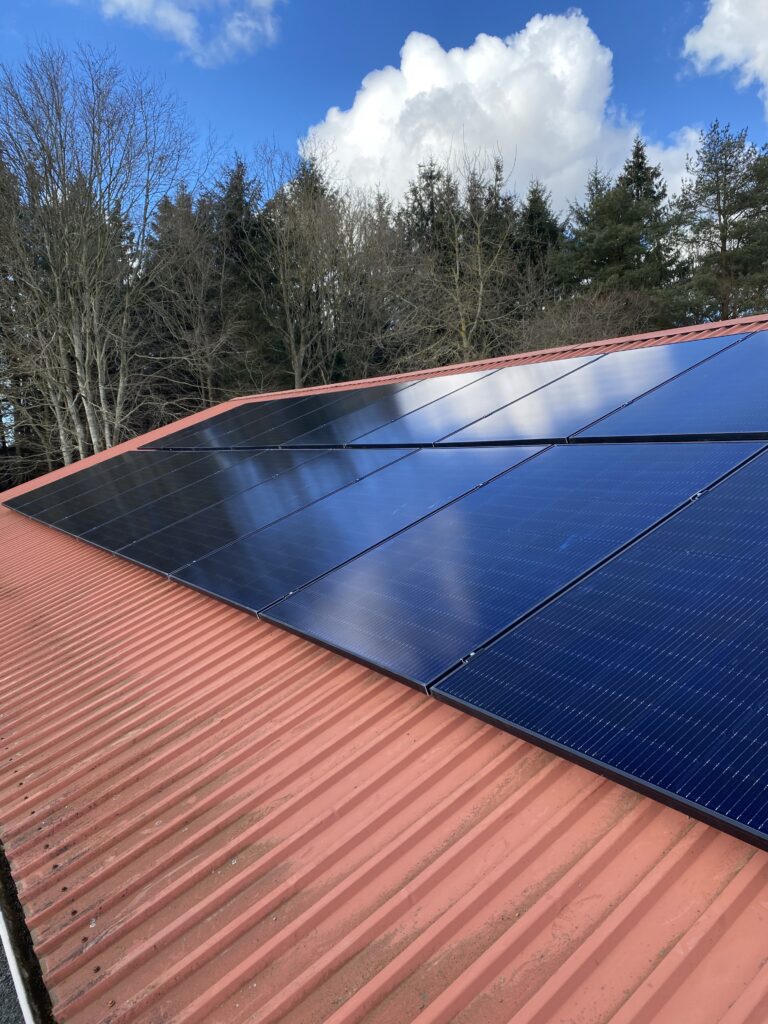 Solpaneler på rødt tag i solskinsvejr